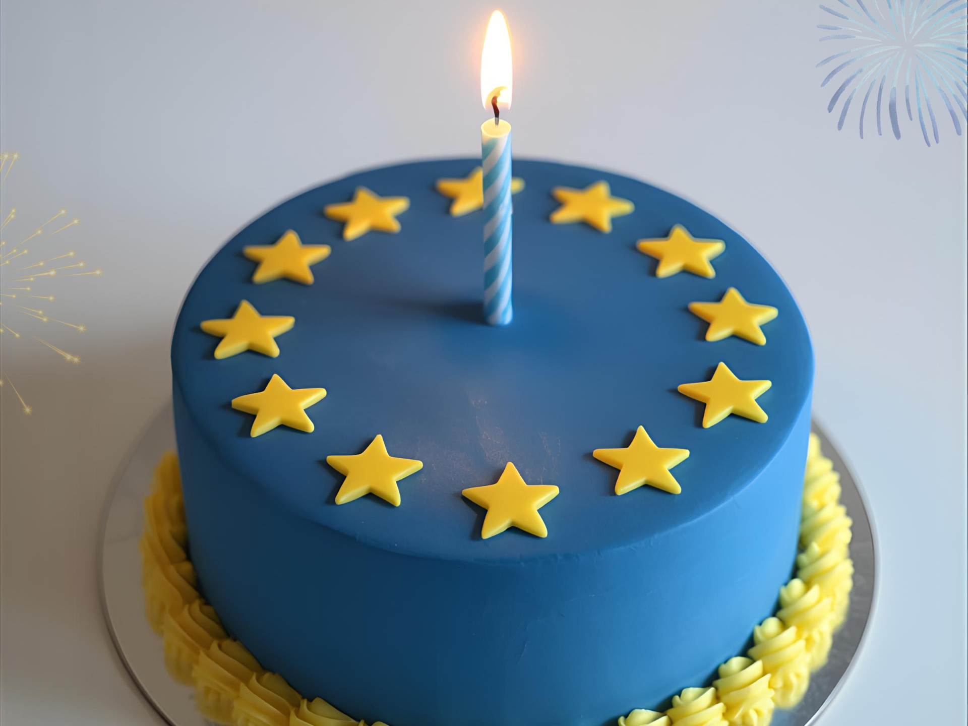 Runder blauer Kuchen mit gelben Sternen in einem Kreis angeordnet, dekoriert wie die Europaflagge, mit einer einzelnen brennenden Kerze in der Mitte